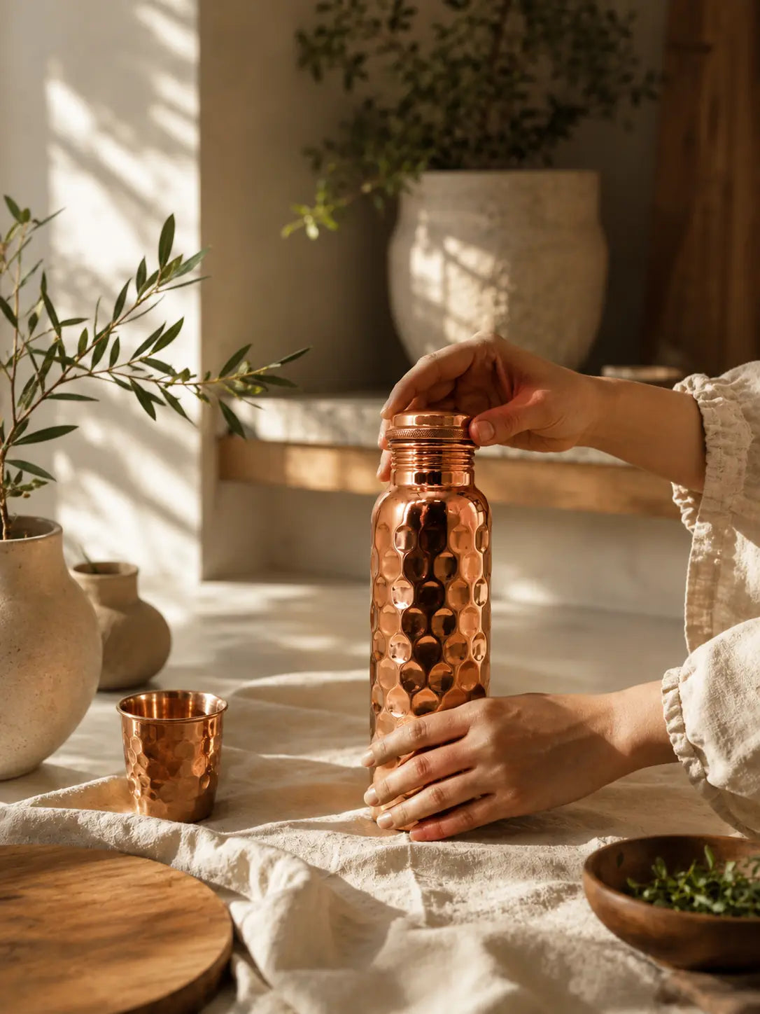 Person holding the Cupreva Diamond Hammered Pure Copper Water Bottle with matching copper tumbler