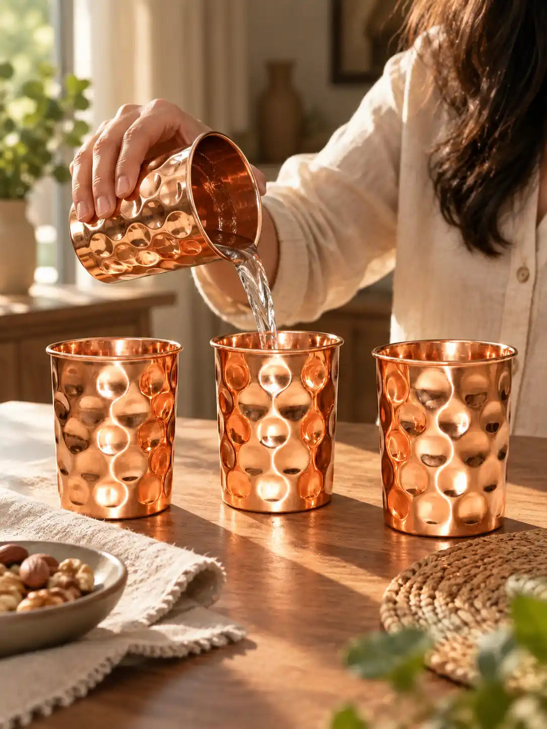 Lifestyle scene showing water being poured into a diamond hammered pure copper water glass