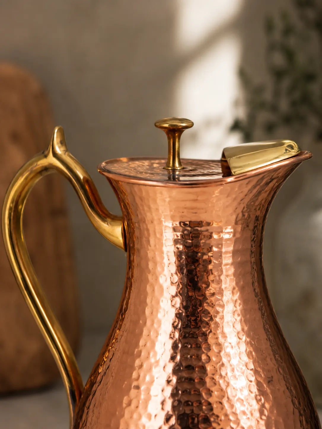 Close-up of the hammered copper finish and brass handle on the Cupreva Royal Water Pitcher