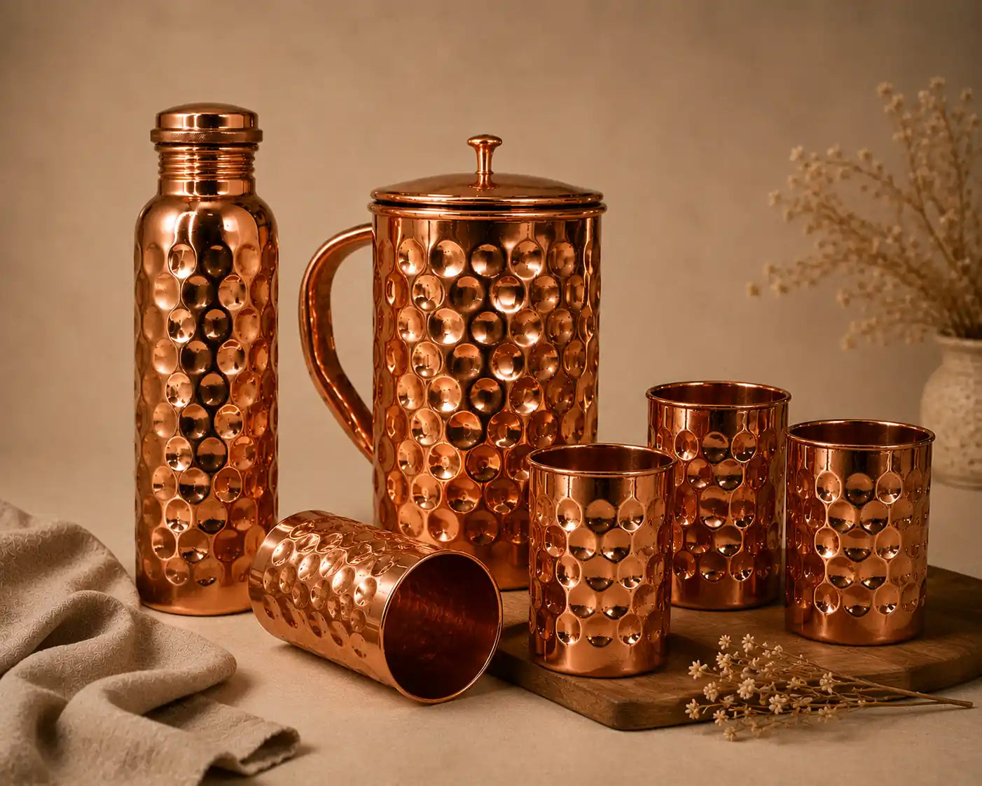Premium hammered copper water bottle, copper pitcher, and four copper drinking glasses arranged for a luxury lifestyle display.
