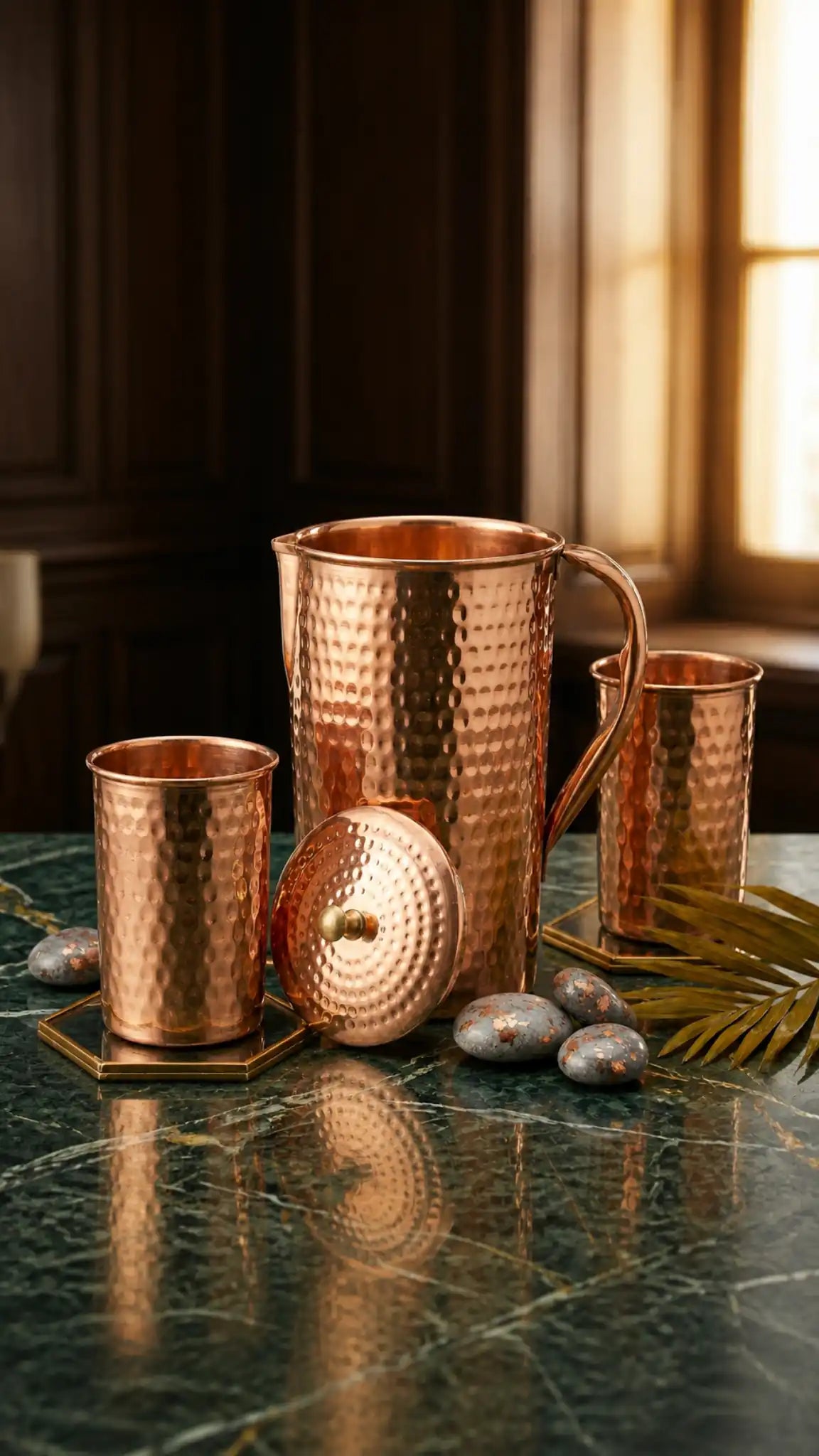 Set of copper mugs and a pitcher on a marble surface with a warm light.