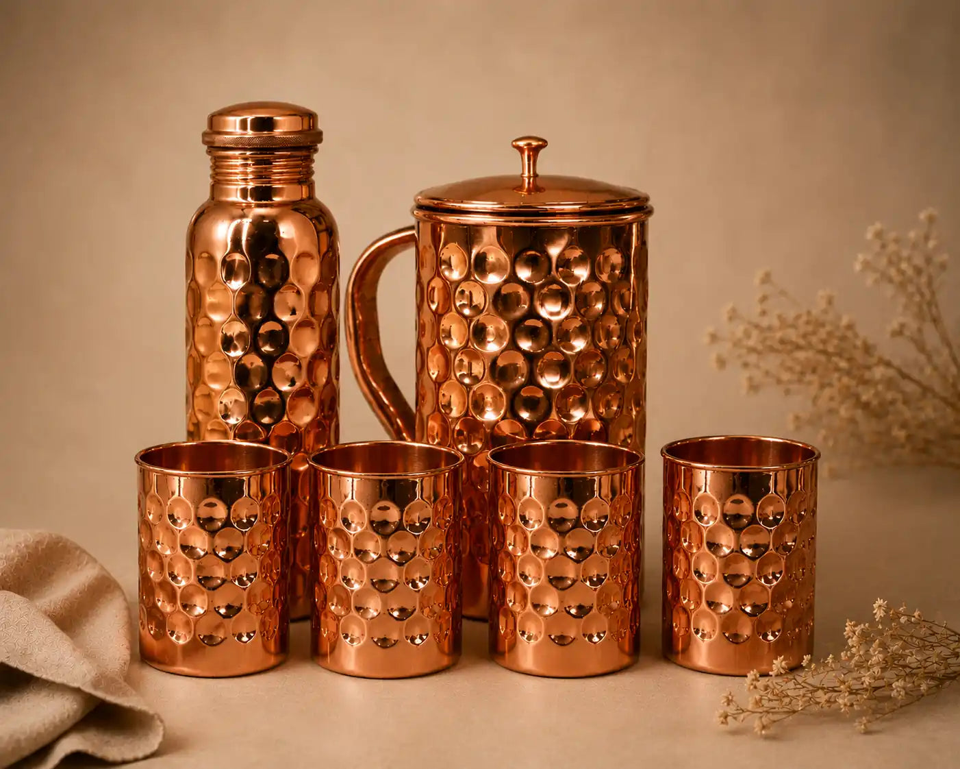 Pure copper drinkware set including a copper water bottle, hammered copper jug, and four matching copper glasses.