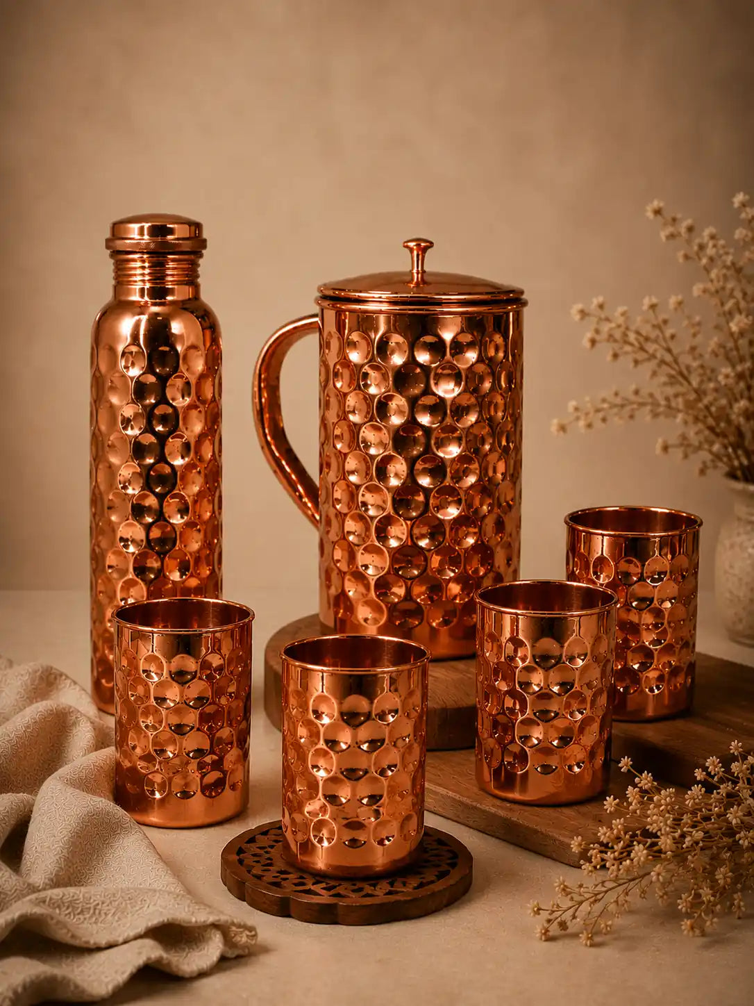 Handcrafted pure copper water bottle, hammered copper jug, and four copper glasses drinkware gift set on a neutral background.