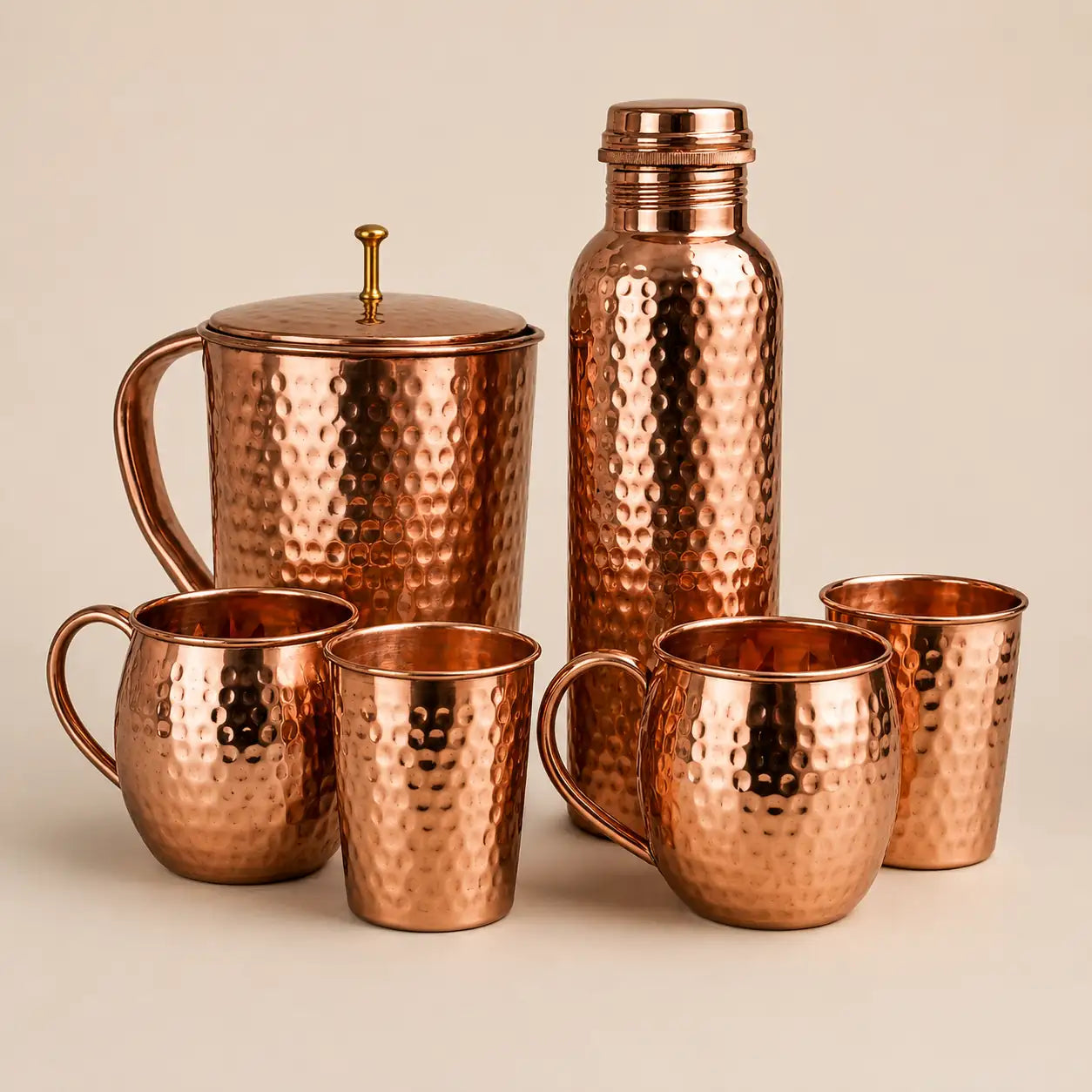 Set of copper mugs and a bottle on a beige background